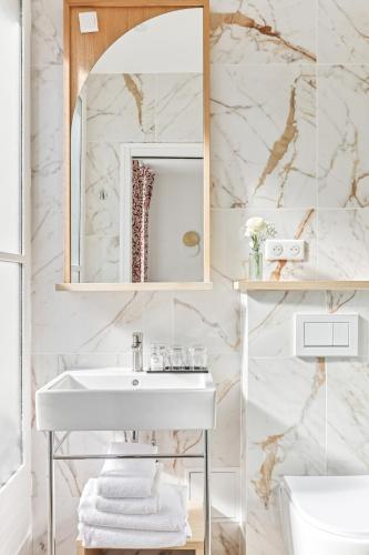 une salle de bain avec un lavabo blanc et un miroir dans l'établissement Hôtel Alexandrine Opera, à Paris