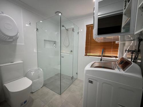 a bathroom with a shower and a toilet and a sink at Parkview 1- Black Head NSW in Hallidays Point