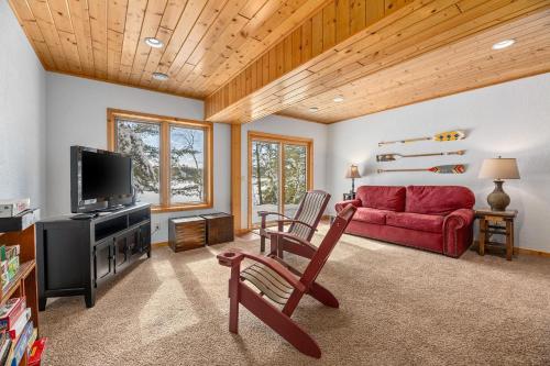 a living room with a red couch and a tv at The Cedar Lakehouse in Lake Tomahawk WI in Lake Tomahawk