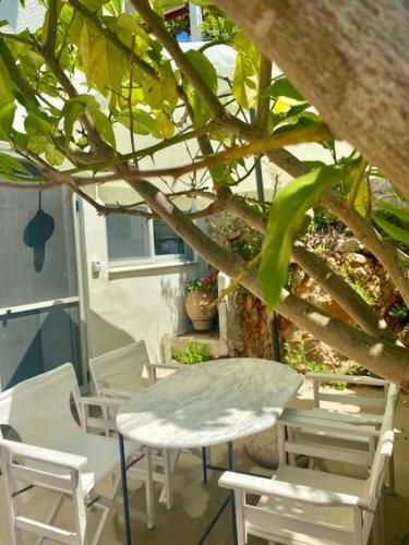 a table and chairs on a porch with a tree at Gianna's Guesthouse & Cave Studio in Pylos