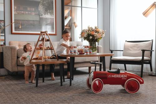 two children sitting at a table with a toy car at Le Méridien Paris Arc De Triomphe in Paris