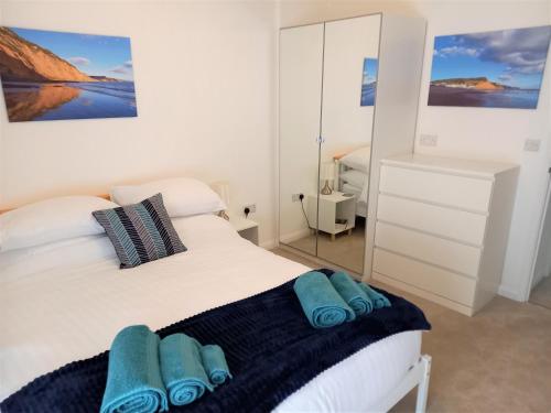 a bedroom with a white bed with blue towels on it at Goviers Cottage in Sidmouth