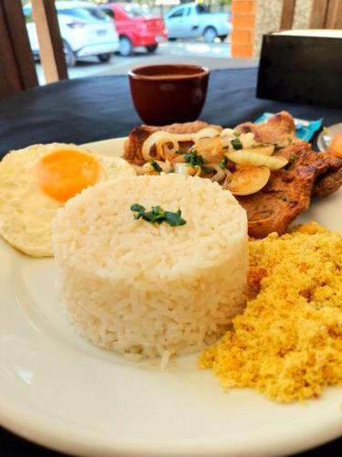 a plate of food with rice and an orange on a table at Cabana in Santo André