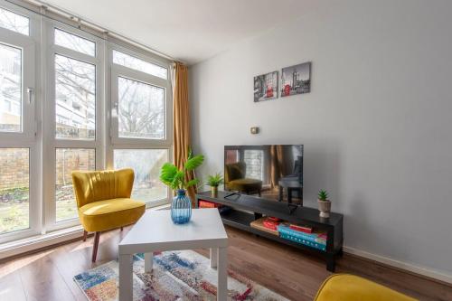 a living room with a tv and a table and chairs at Lovely 2-bed 20 mins to central London in London