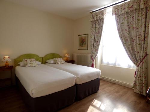 a bedroom with a large bed and a window at Hôtel La Tonnellerie in Beaugency