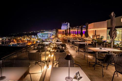a restaurant with tables and chairs on a balcony at night at Silken Saaj Maar - Adults Only in Puerto de la Cruz