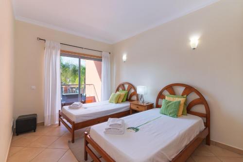 zwei Betten in einem Zimmer mit Fenster in der Unterkunft Jardins Vale de Santa Maria G, with pool in Albufeira