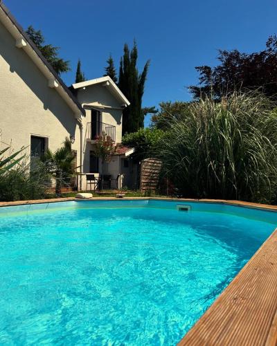 une grande piscine bleue devant une maison dans l'établissement La cigale et la fourmi savoisienne - chambre chez l habitant, à Aix-les-Bains