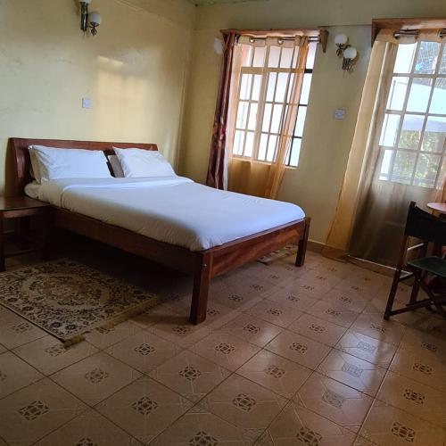 a bedroom with a bed in a room with windows at Vivid Spaces in Nanyuki