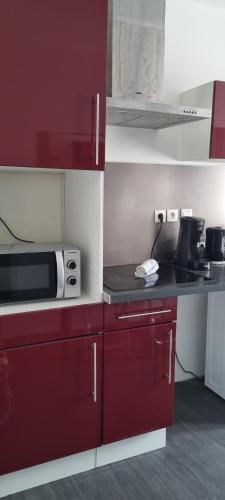une petite cuisine avec des placards rouges et un four micro-ondes dans l'établissement Coeur de ville, à Sète
