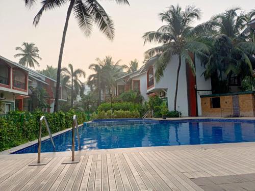ein Swimmingpool vor einem Haus mit Palmen in der Unterkunft Heritage Exotica 2BHK Apartment service apartments in goa in Arpora