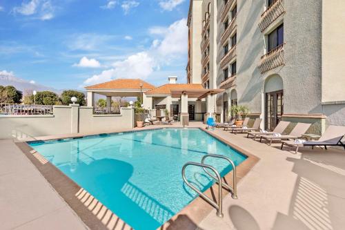 a swimming pool with chairs and a building at Best Western Plus Heritage Inn Ontario Rancho Cucamonga in Rancho Cucamonga