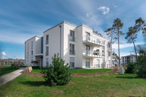 a white building with a tree in front of it at Ferienwohnung "Haffhafen" Hunde willkommen in Zirchow
