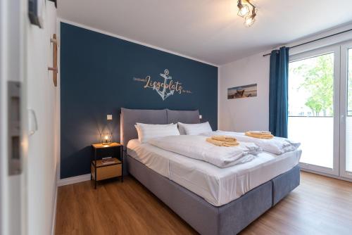 a bedroom with a large bed with a blue wall at Ferienwohnung "Haffhafen" Hunde willkommen in Zirchow