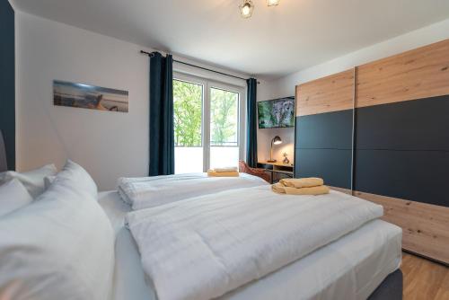 a bedroom with a large white bed with a large window at Ferienwohnung "Haffhafen" Hunde willkommen in Zirchow