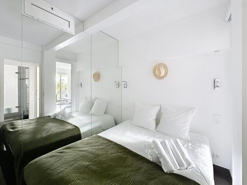 - une chambre blanche avec 2 lits et un miroir dans l'établissement One bedroom apartment on La Croisette - Sea view, à Cannes