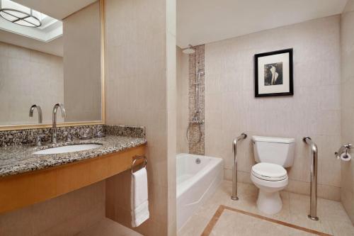a bathroom with a toilet and a sink and a tub at Sheraton Xi'an Hotel in Xi'an