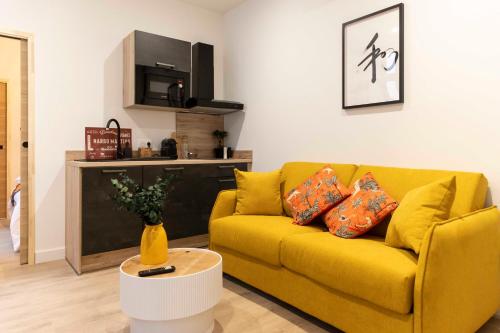 un salon avec un canapé jaune et une table dans l'établissement Thomas Price Appart, à Narbonne