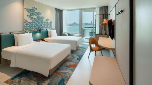 a hotel room with two beds and a desk at Holiday Inn Pattaya by IHG in Pattaya Central
