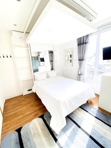 une chambre avec un lit blanc et une grande fenêtre dans l'établissement Paris Eiffel Studio, à Paris