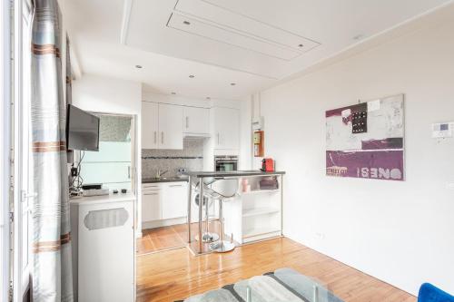 une cuisine avec des armoires blanches et une table dans une pièce dans l'établissement Paris Eiffel Studio, à Paris