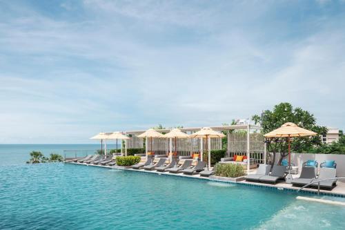 a pool with chairs and umbrellas and the ocean at Holiday Inn Pattaya by IHG in Pattaya Central