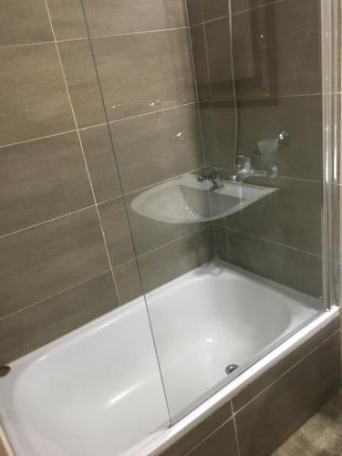 a bath tub with a shower and a sink at Apart Duclout Monte Grande a 15 minutos del Aeropuerto Ezeiza in Monte Grande