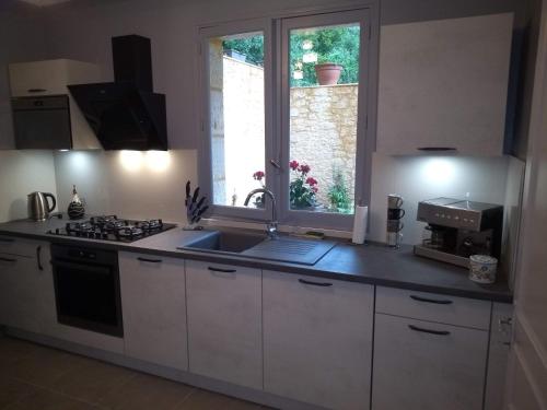 une cuisine avec un évier, une cuisinière et une fenêtre dans l'établissement LA VILLA DES HAUTS DE SARLAT, à Sarlat-la-Canéda