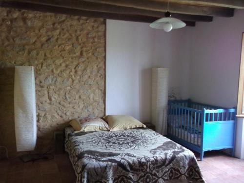 1 dormitorio con cama y pared de piedra en Gite Tauzia, en Brassempouy