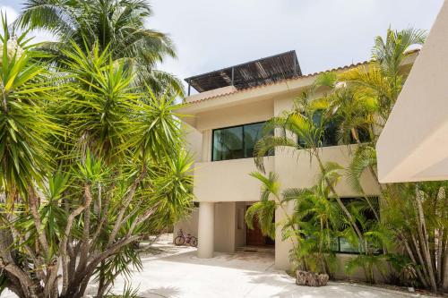une maison avec des palmiers devant dans l'établissement Magnifica casa laguna cerca de la playa., à Puerto Aventuras