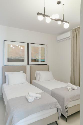 two beds in a room with white walls at Ocean Breeze in Chrysi Ammoudia