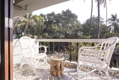 a group of white chairs and a table on a patio at Hotel Lotus in Candolim