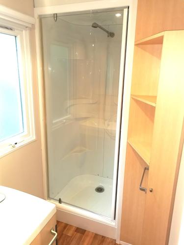 une douche avec une porte vitrée dans une salle de bain dans l'établissement MH Topconfort 2ch 5pers 900DA, à La Boissière-de-Montaigu