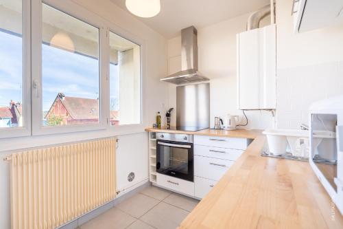 une cuisine avec des placards blancs et une grande fenêtre dans l'établissement Appartement de charme à Digoin #2, à Digoin