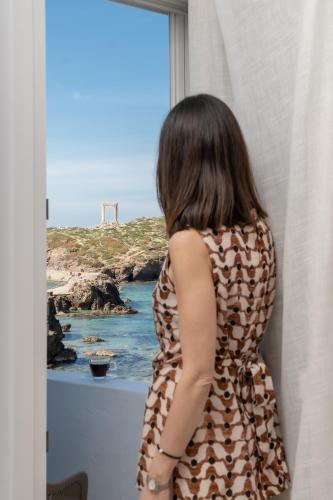 a woman looking out a window at the ocean at Flèria Seaview Suites in Naxos Chora