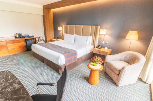 a hotel room with a bed and a chair at Sonesta Hotel El Olivar in Lima