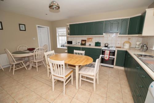 a kitchen with green cabinets and a table and chairs at GlebeH Self Catering in Banagher