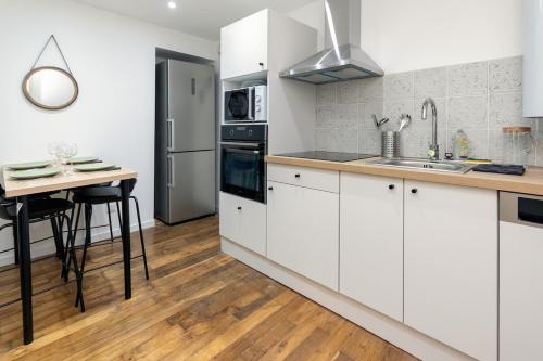 a kitchen with white cabinets and a wooden floor at OriOn in Briey