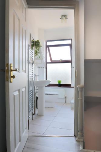 a white bathroom with a sink and a window at 2 Bed Home-Cheltenham-Sleeps 6-Work or Leisure in Cheltenham