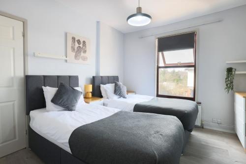 a bedroom with two beds and a window at 2 Bed Home-Cheltenham-Sleeps 6-Work or Leisure in Cheltenham