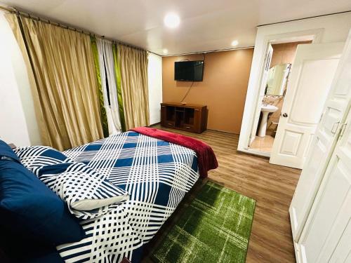 a hotel room with a bed and a television at Confort Home Apartamentos Vacacionales in Baños