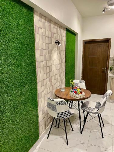 a table and chairs in a room with a green wall at Beachfront Studios by Virani in Karachi
