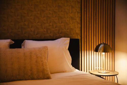 - une chambre avec un lit doté d'oreillers blancs et d'une lampe dans l'établissement La Môme — Parking, quartier historique & animé, à Caen