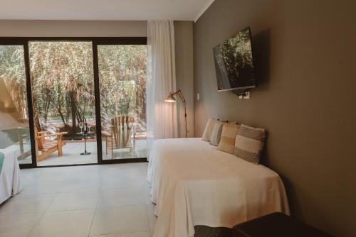 a bedroom with a bed and a sliding glass door at Puerto Dijama Hotel Boutique in Carmelo