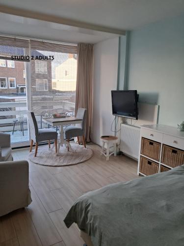 a room with a bed and a table and a tv at El Sol Zandvoort 2 in Zandvoort