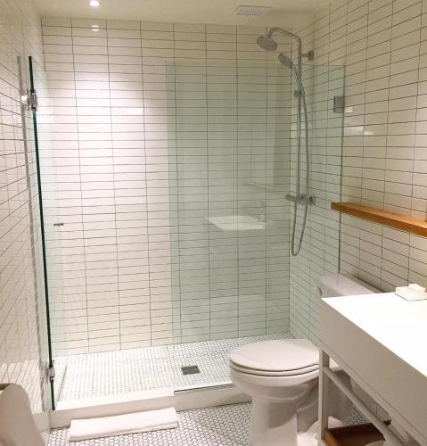 a bathroom with a shower with a toilet and a sink at The Asbury Hotel in Asbury Park