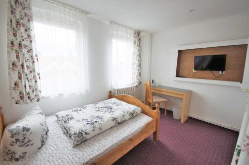 Dormitorio con cama, escritorio y TV en Hotel Am Kurpark en Bad Suderode