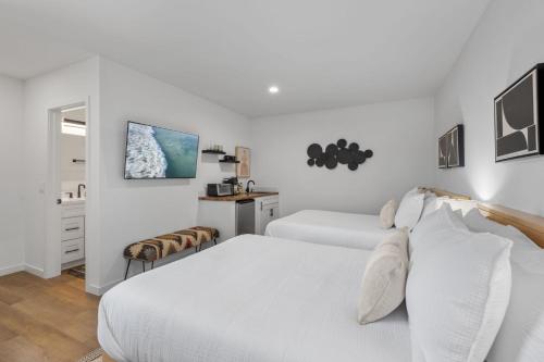 ein weißes Schlafzimmer mit zwei Betten und einem Tisch in der Unterkunft South O Bungalow 7 - Premium Double Studio + Patio in Oceanside