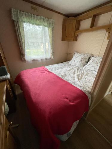 - un petit lit dans une petite chambre avec fenêtre dans l'établissement Mobilhome des Quatre Terres, à Lesparre-Médoc