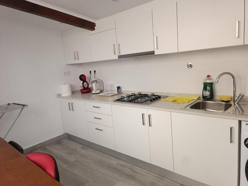 a white kitchen with white cabinets and a sink at Casalondres emTR77 in Lisbon